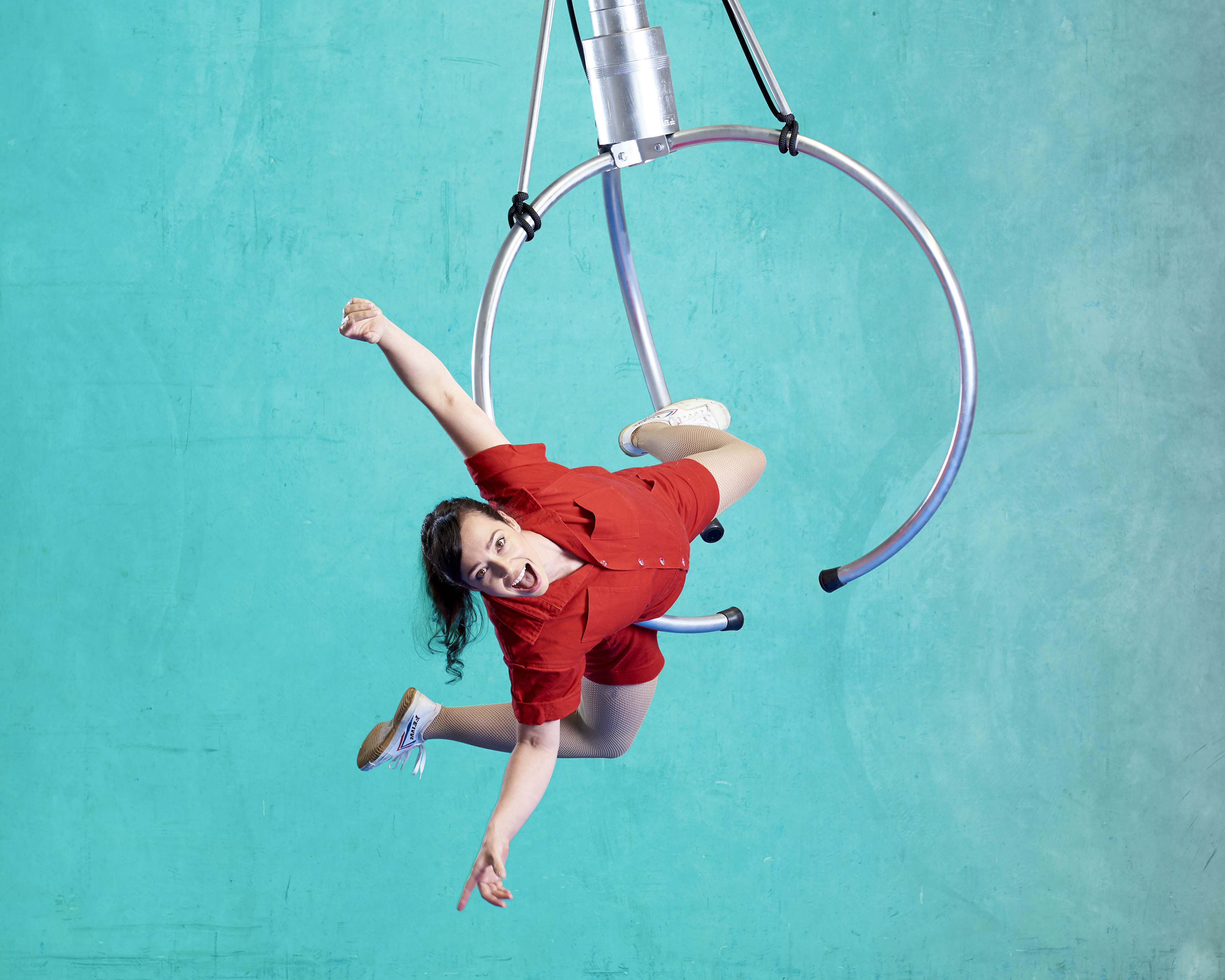 Circus performer hangs upside down on a ring. 