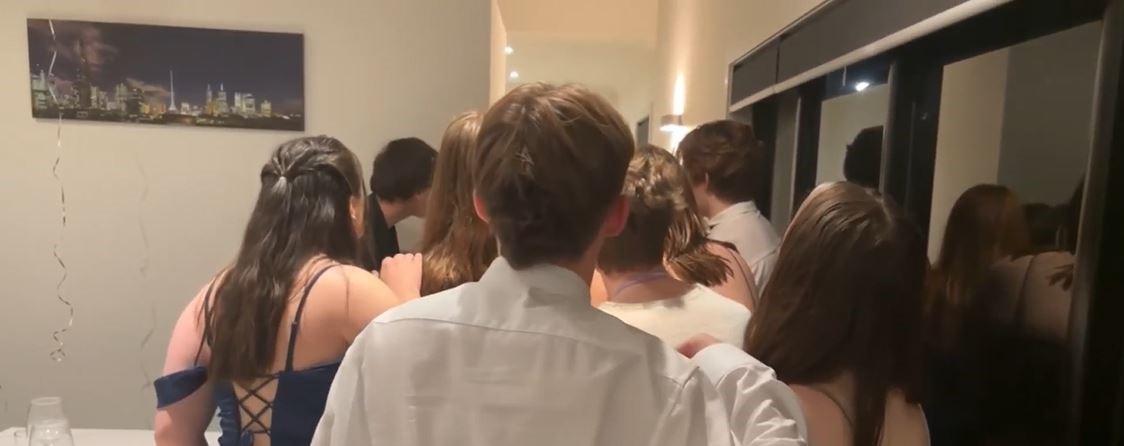 group of people dressed in formal attire gathering to look at something in the distance