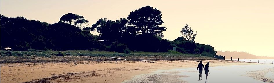two people walking on the beach