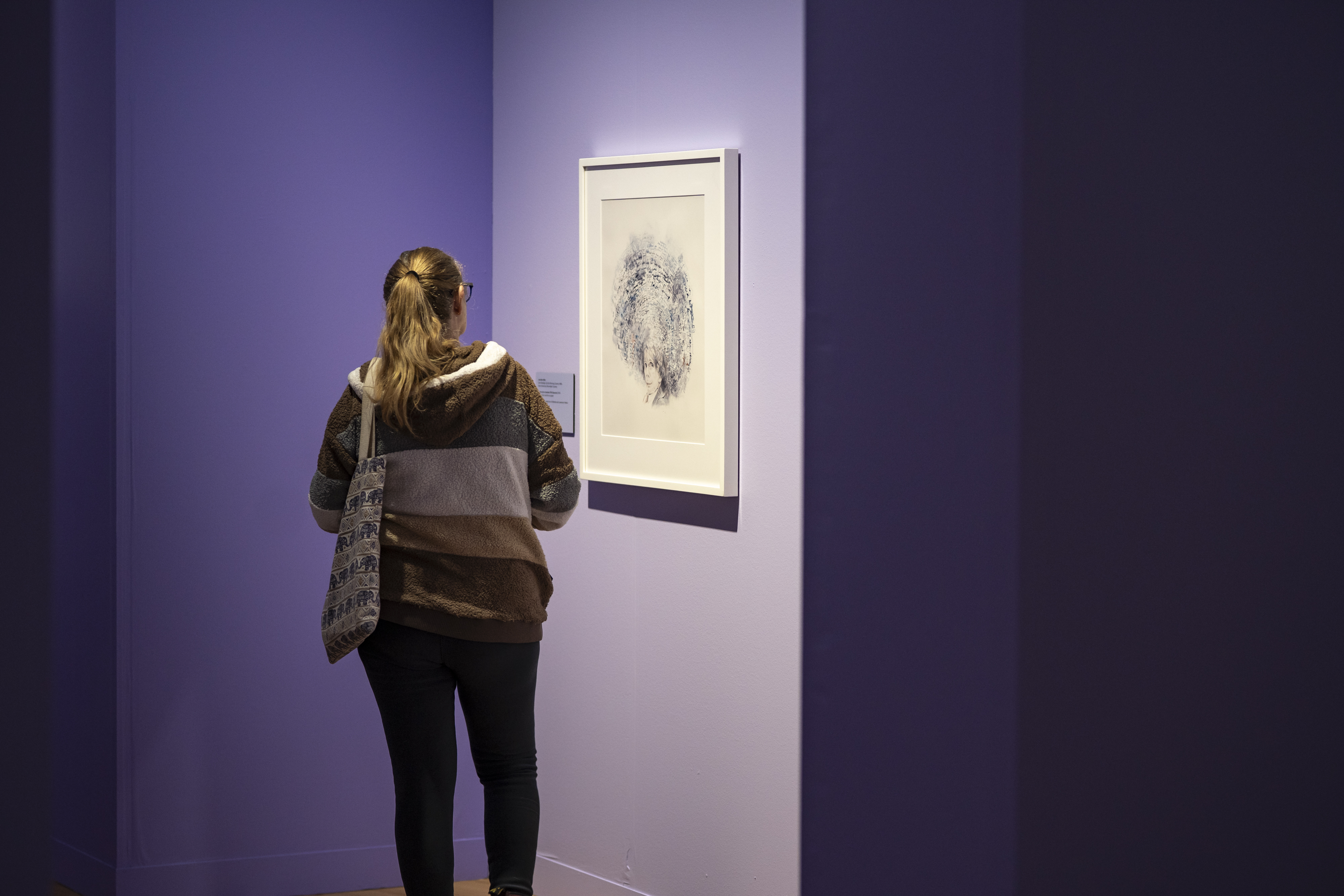 a person looking at an artwork with a purple background