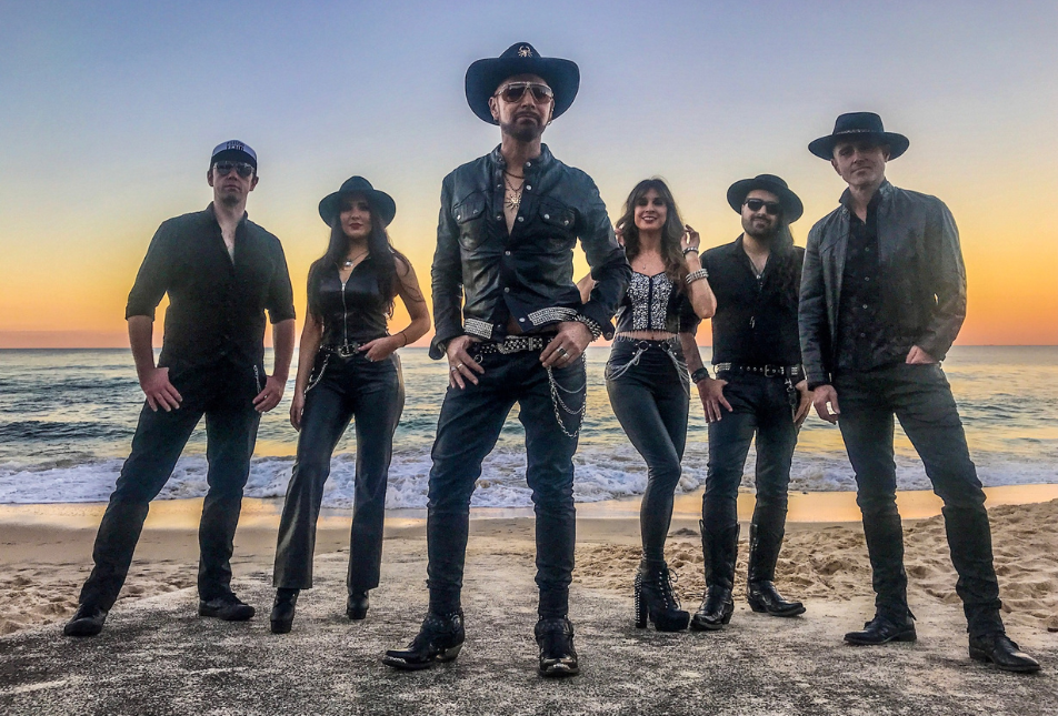 Six people in dark clothing stands against a bright sunset - members of Pseudo Echo