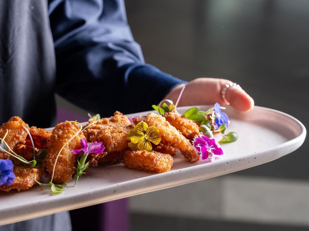 A waiter holding a platter of fried chicken
