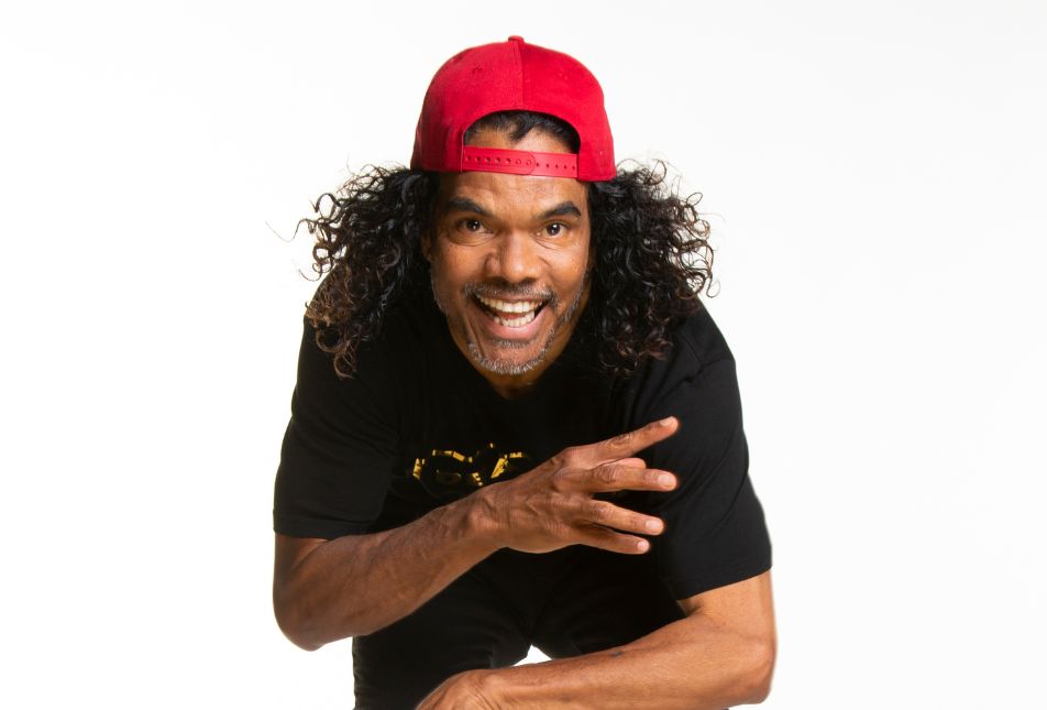 A man with a red cap on backwards laughs at the camera