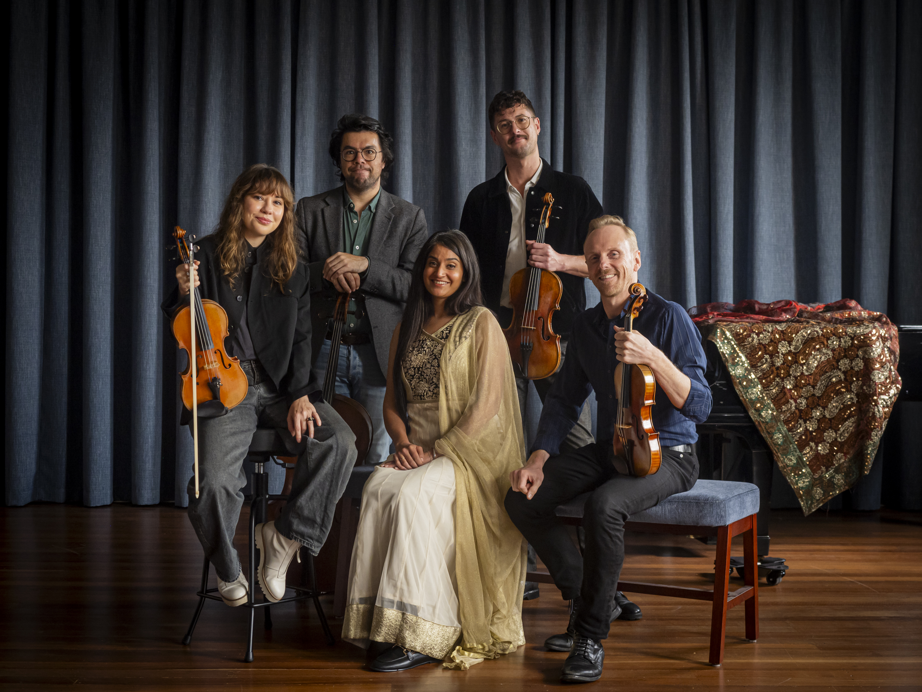 Four musicians from the Australian String Quartet stand with their intruments around Parvyn, a South Asian woman in a gold sari, who is seated.