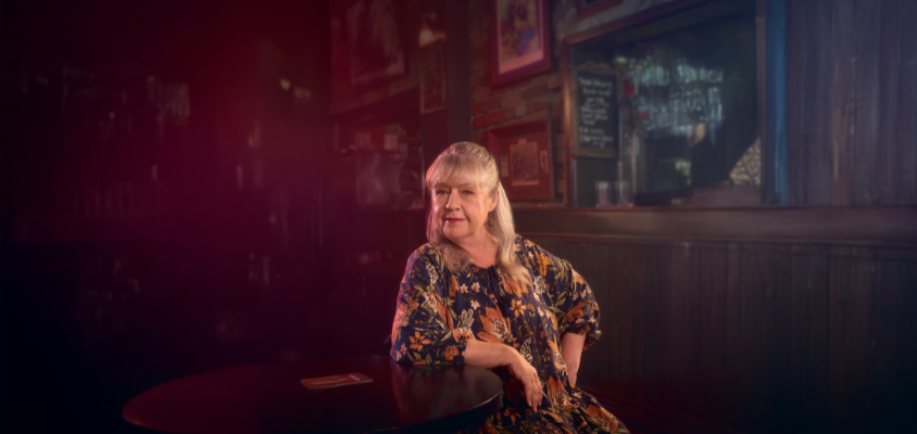 A woman sits at a bar table in a bar. 