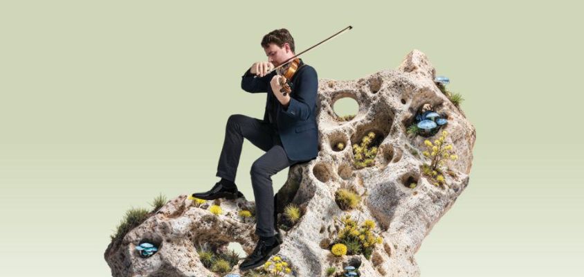 A man playing a violin looking like he is sitting on a large piece of coral