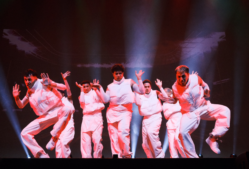 A hip hop dance crew in white outfits on stage