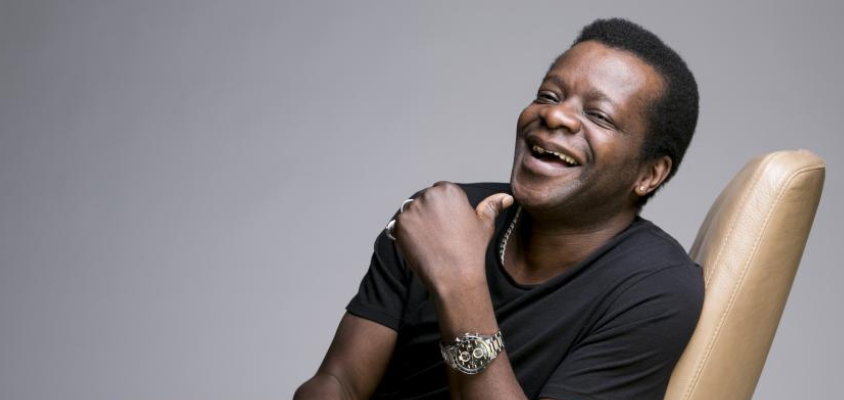 A man laughs, reclining in a chair