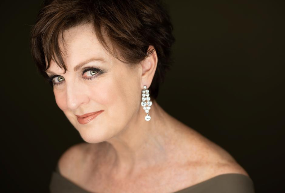 A woman with large sparkly earrings smiles at the camera
