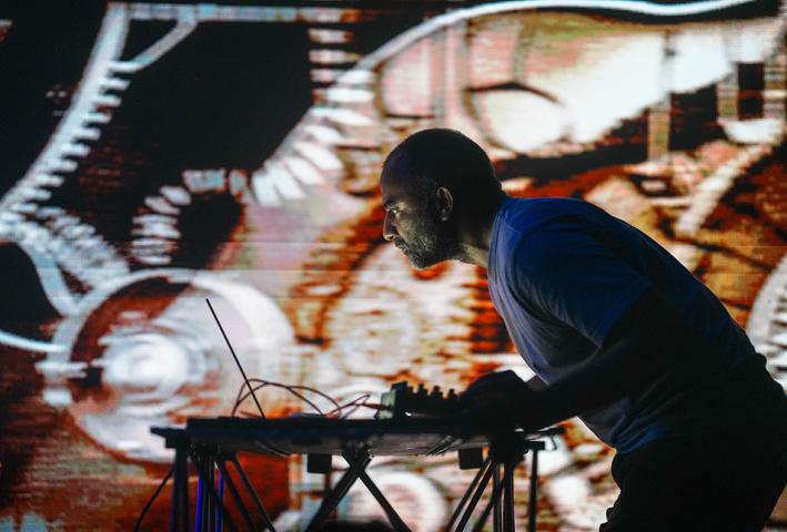 A dj in silhouette against a bright lit digital background