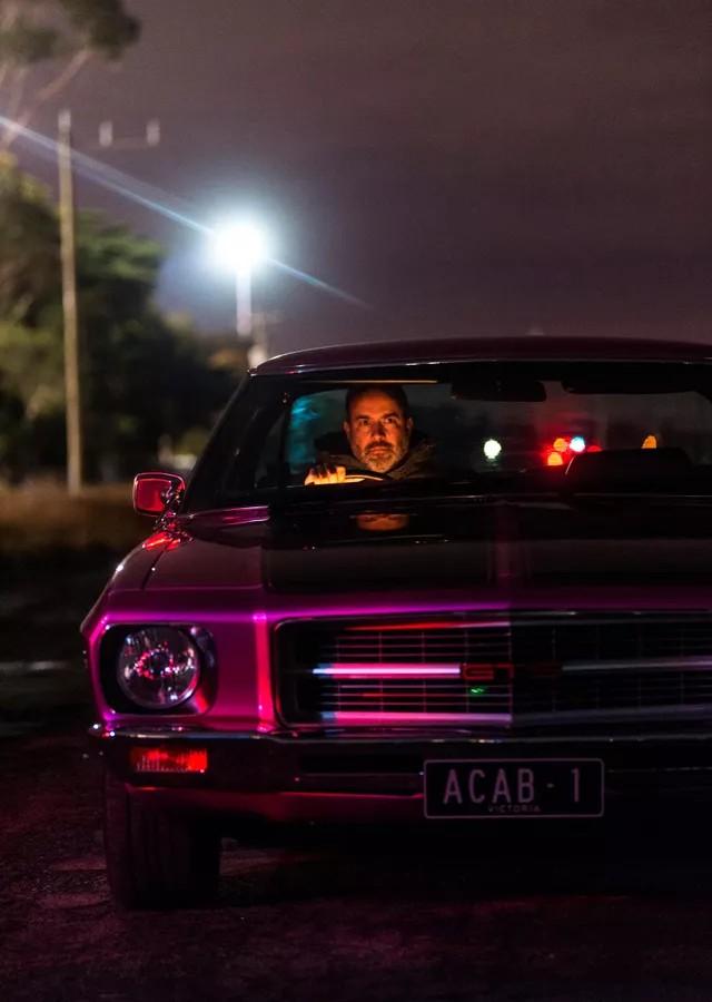 A man driving a purple car at night