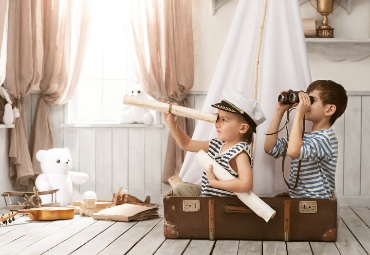 Kids exploring the world, sitting in an old suitcase will a rolled up paper telescope.