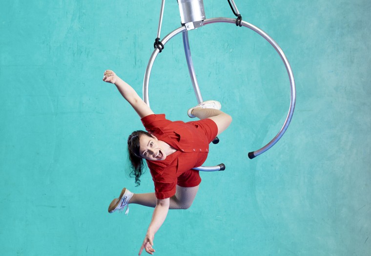 Circus performer hangs upside down on a ring. 