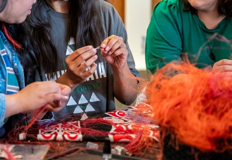 close up shot of hands making earrings using muka fiber
