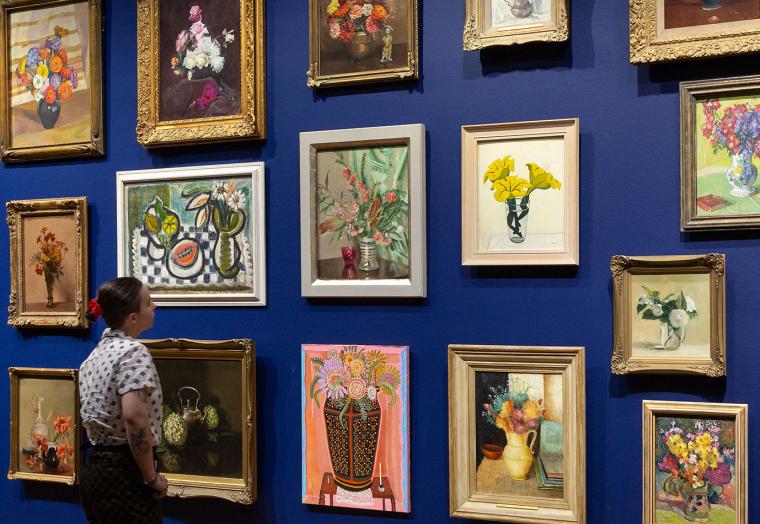 Salon hang of paintings with a person standing in front of the wall looking at the paintings