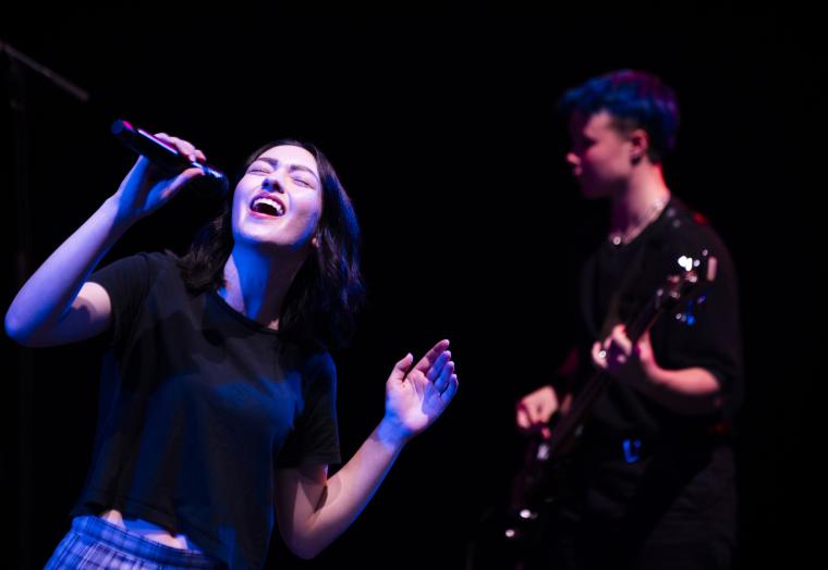 Young singer with a microphone and guitarist in the background