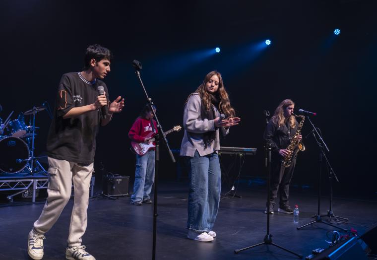 Young students performing on stage in a band dressed in casual clothes