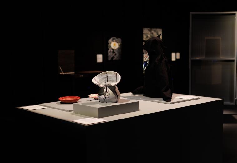 installation view of a display featuring a ceramic vase, a black hoodie and rope bowls