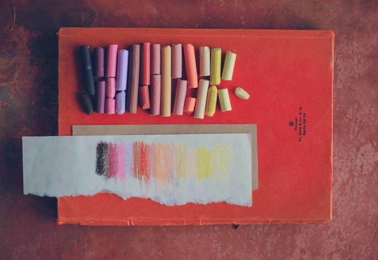flatlay of a red book with oil pastels on top