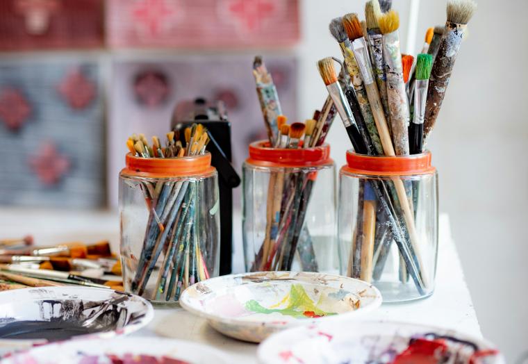 a table with bowls of paint and jars of paint brushes