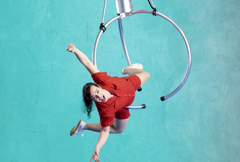 Circus performer hangs upside down on a ring. 