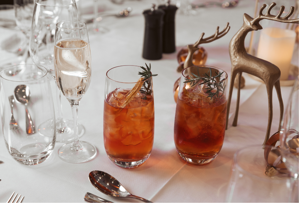 A table setting for Christmas, with two glasses, and a reindeer statue