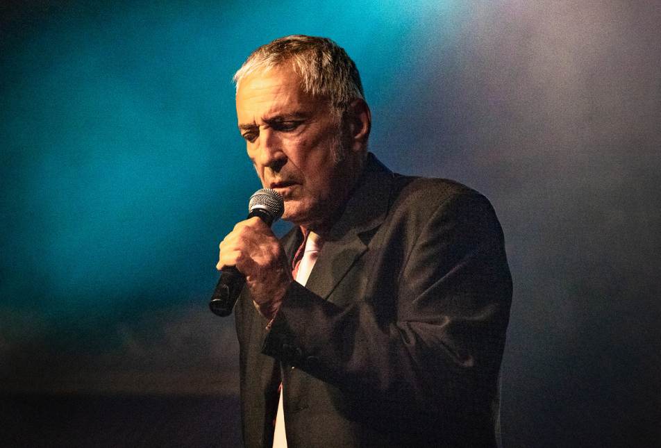 A man in a suit sings into a microphone