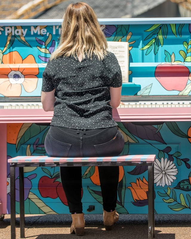 young woman playing public piano