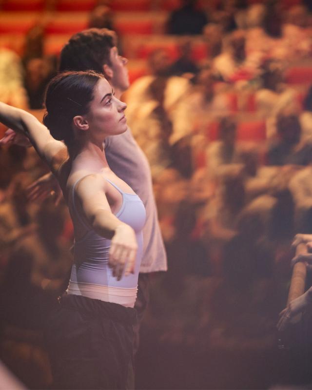 Ballet dancers performing on stage, watched by an audience