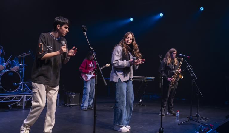 Young students performing on stage in a band dressed in casual clothes