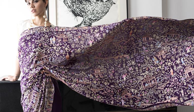 a purple sari with white embroidery extended to to show its length