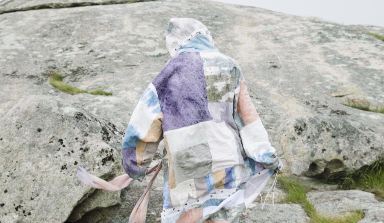 person standing with their back to the camera, in front of a granite boulder