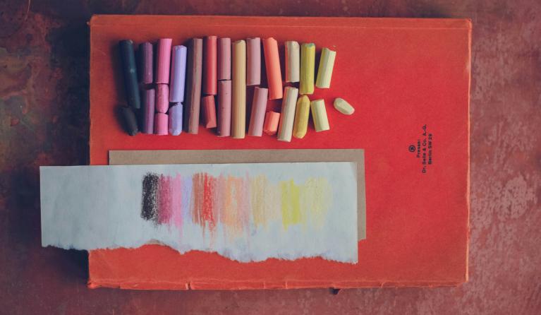 flatlay of a red book with oil pastels on top