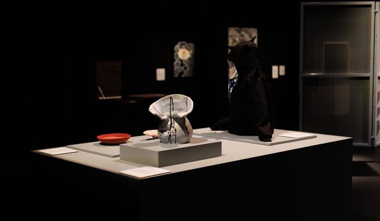installation view of a display featuring a ceramic vase, a black hoodie and rope bowls