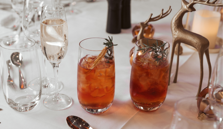 A table setting for Christmas, with two glasses, and a reindeer statue