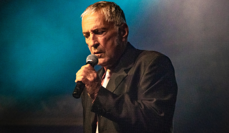 A man in a suit sings into a microphone