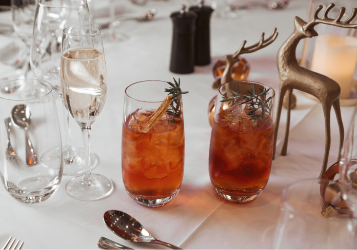 A table setting for Christmas, with two glasses, and a reindeer statue