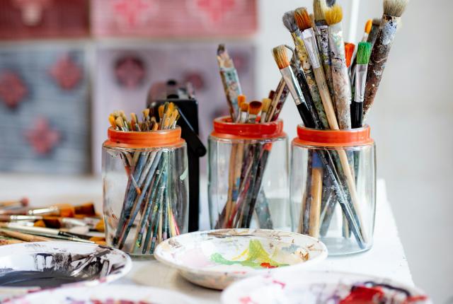 a table with bowls of paint and jars of paint brushes