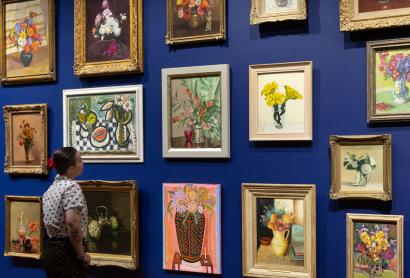 Salon hang of paintings with a person standing in front of the wall looking at the paintings