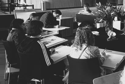 group of people sitting down drawing a still life display