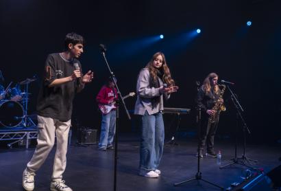 Young students performing on stage in a band dressed in casual clothes