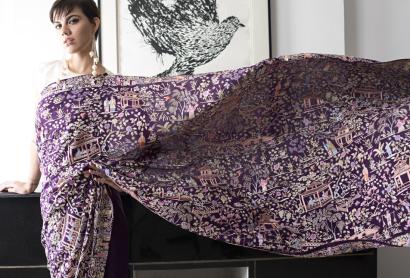 a purple sari with white embroidery extended to to show its length